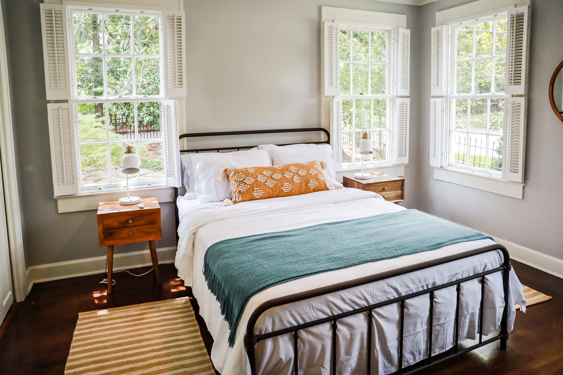 A guest bedroom with a queen sized bed and nightstand at a short term rental small cottage style house